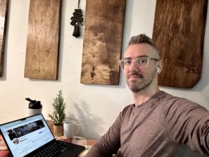 Inner Circle Member Kyle Dammann making a facebook post in a cafe